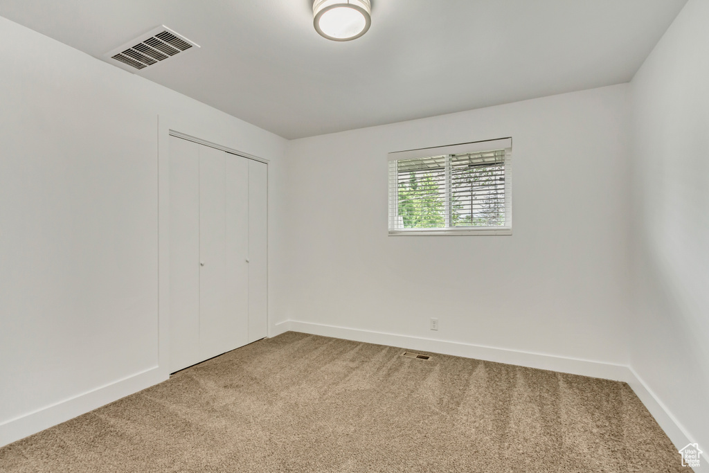 Unfurnished bedroom with light colored carpet and a closet