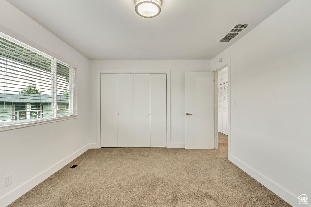 Unfurnished bedroom featuring light carpet and a closet