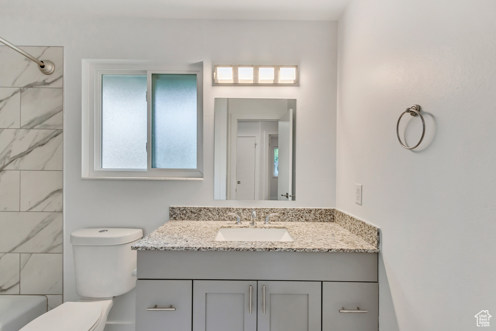 Full bathroom featuring tiled shower / bath combo, toilet, and vanity