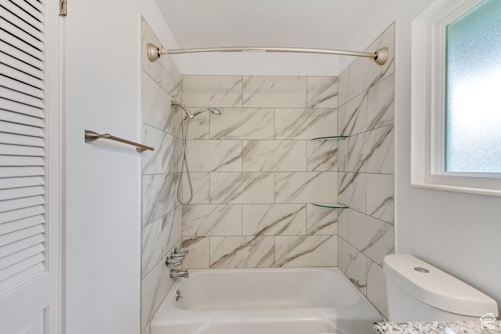 Bathroom with tiled shower / bath combo and toilet