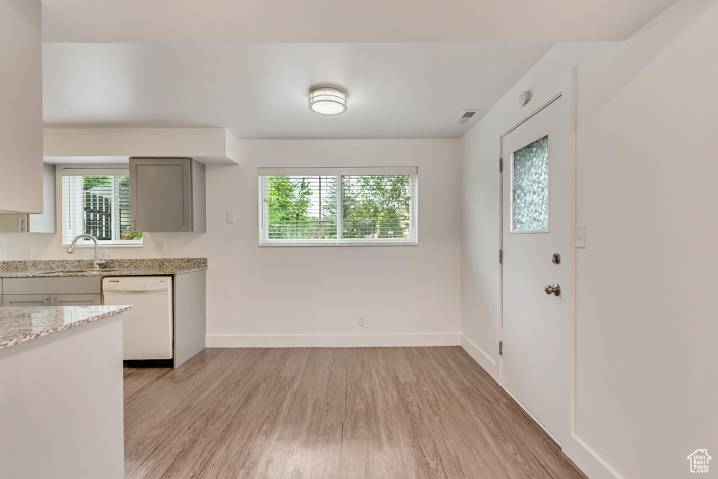 Kitchen with white dishwasher, light wood-type flooring, and plenty of natural light