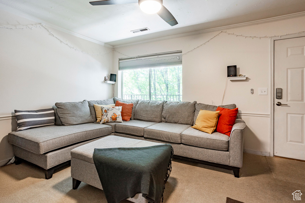 Living room with ceiling fan, light colored carpet, and ornamental molding
