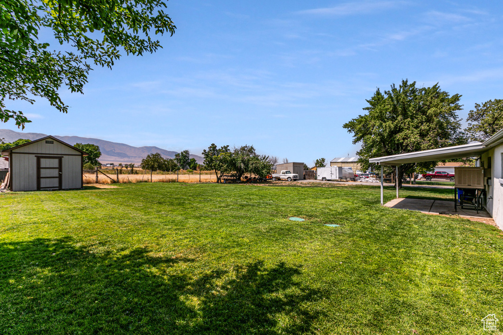 View of yard featuring a mountain view, a patio area, a carport, and a shed