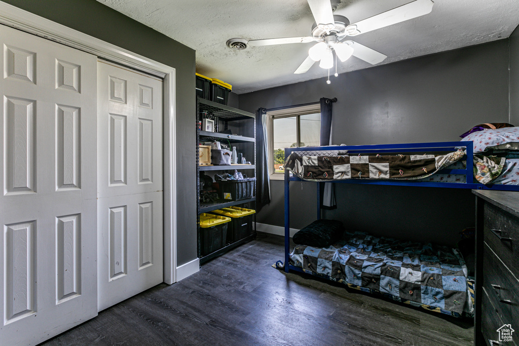 Bedroom with a textured ceiling, ceiling fan, wood-type flooring, and a closet