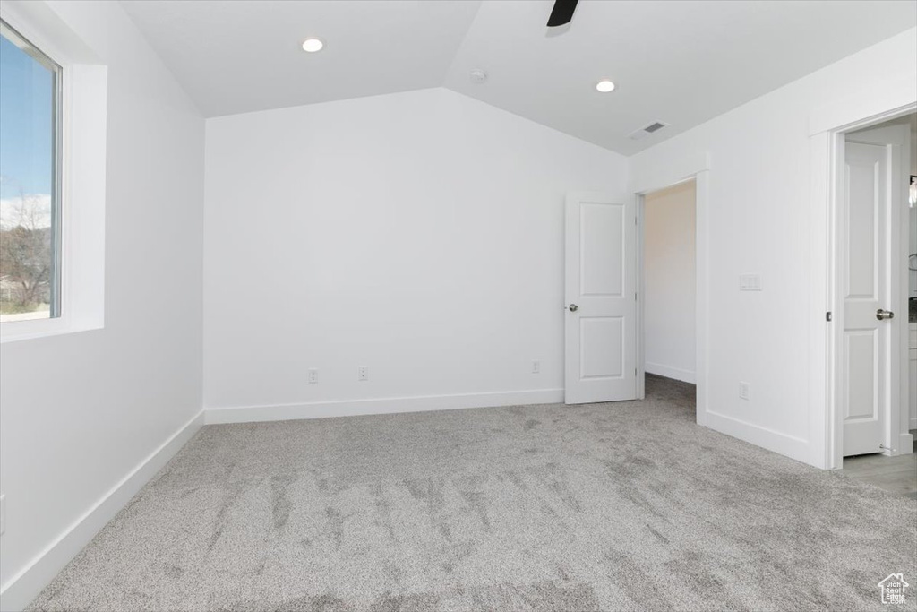 Interior space featuring ceiling fan, vaulted ceiling, and light carpet