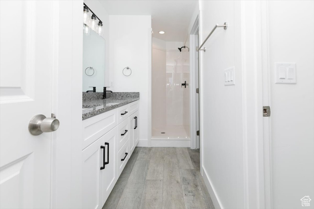 Bathroom with hardwood / wood-style flooring, a shower, and vanity