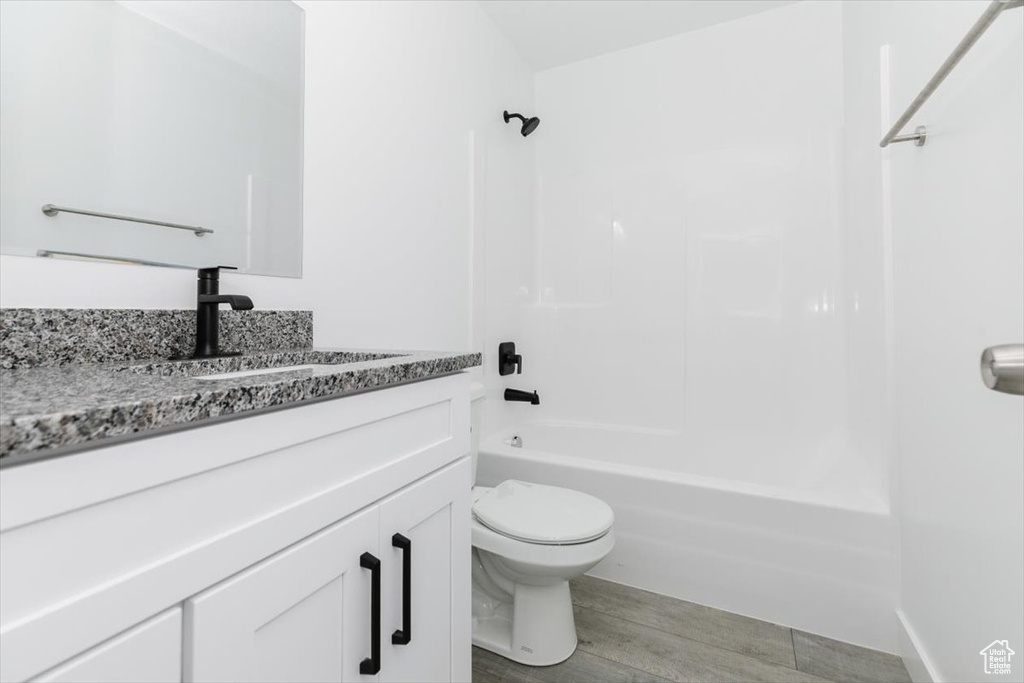 Full bathroom featuring shower / bathtub combination, vanity, hardwood / wood-style floors, and toilet