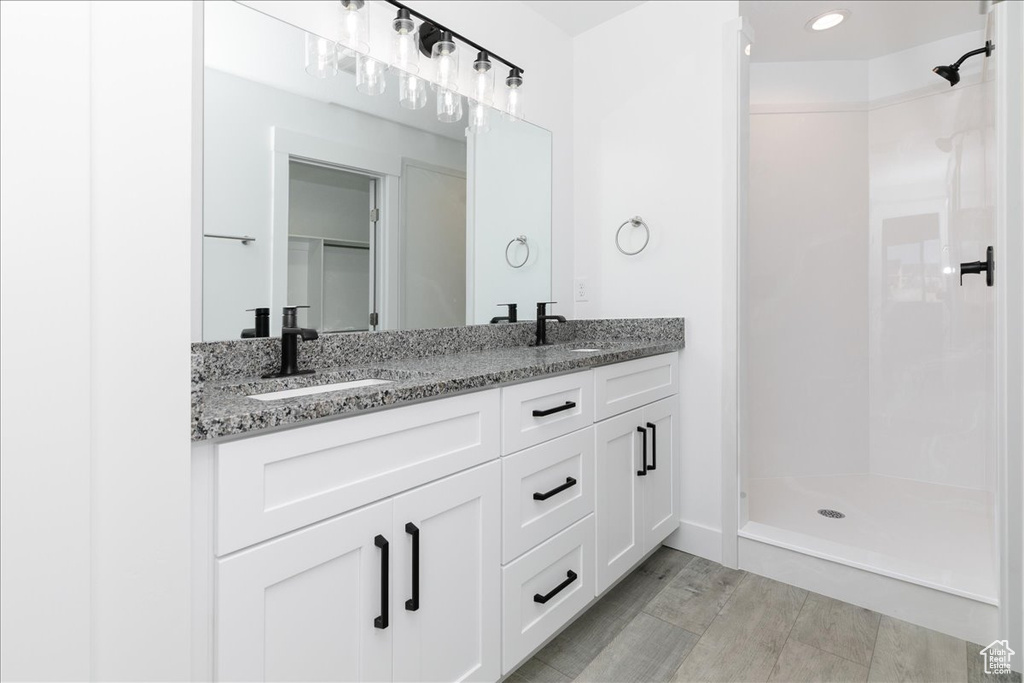 Bathroom featuring hardwood / wood-style floors, a shower, and vanity