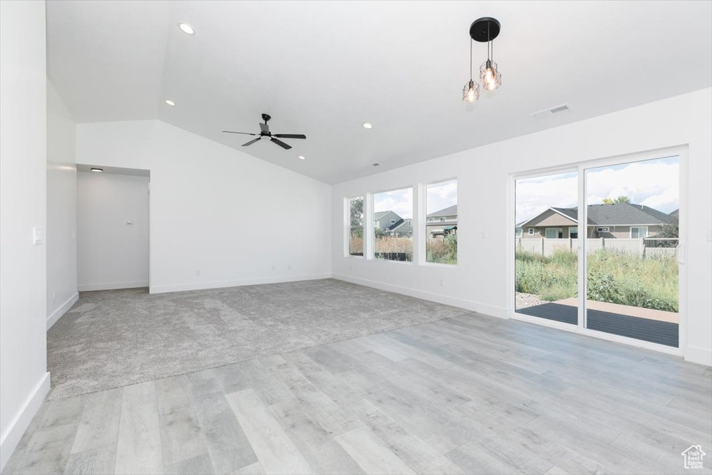 Unfurnished living room with ceiling fan, light carpet, and lofted ceiling