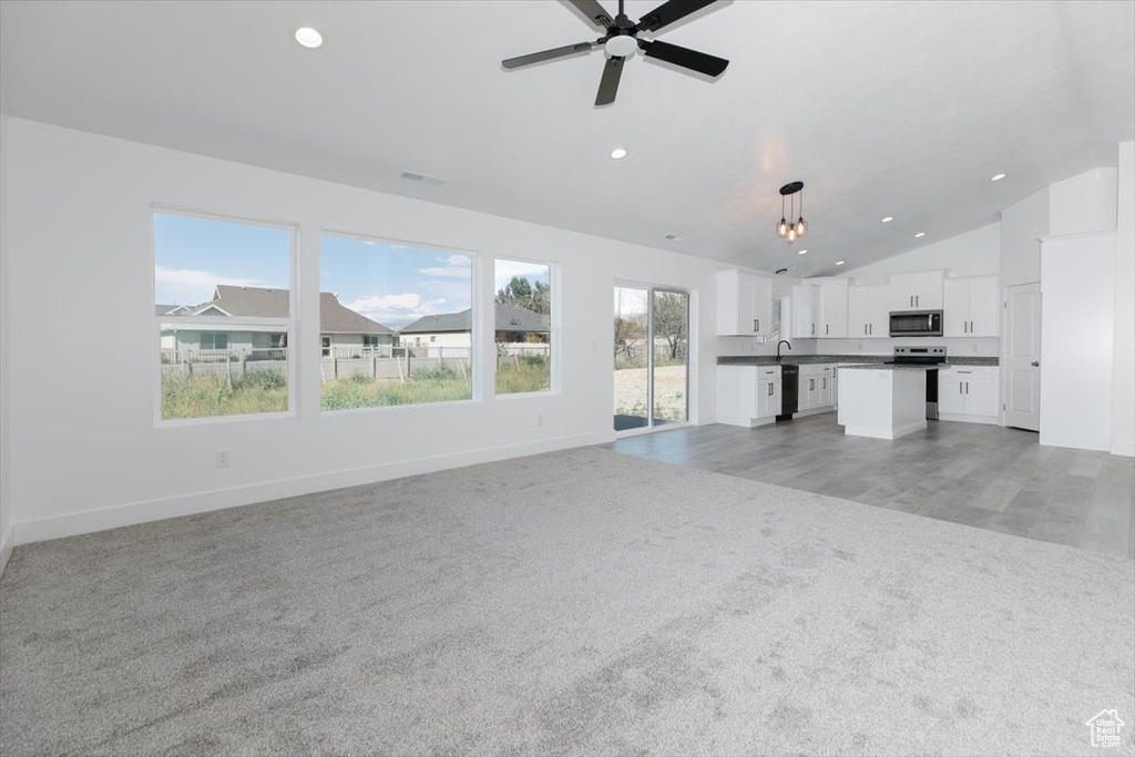 Unfurnished living room with sink, ceiling fan, a healthy amount of sunlight, and light colored carpet