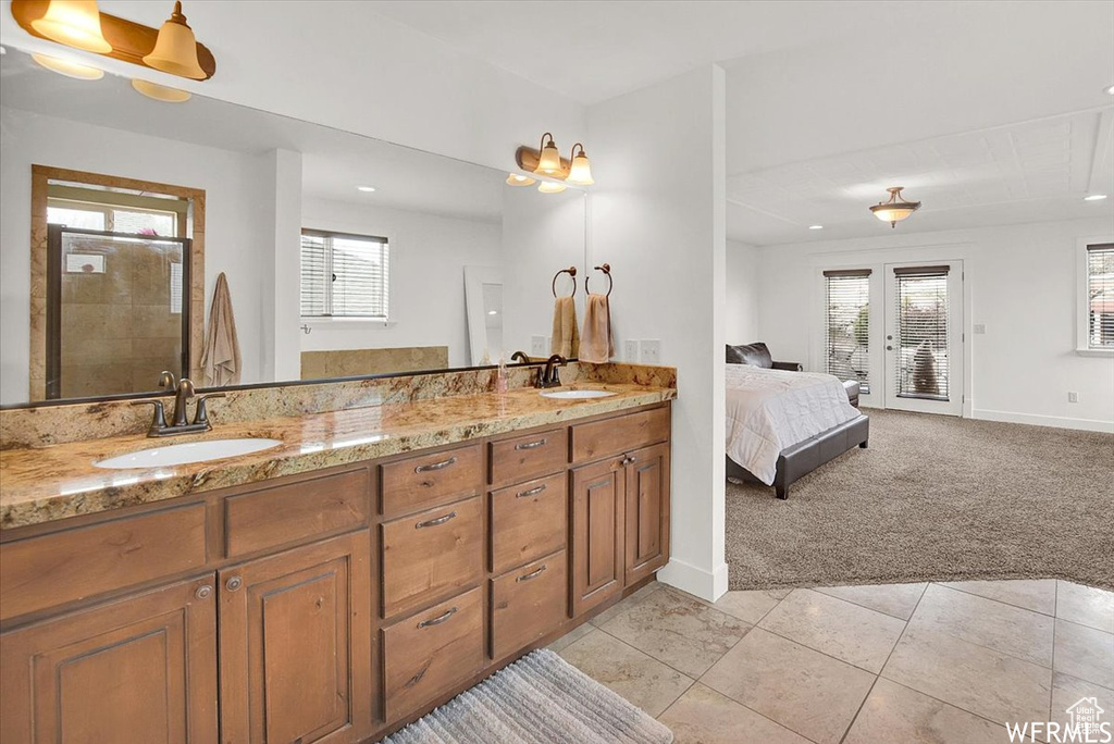 Bathroom featuring tile patterned flooring, double sink vanity, french doors, and tiled shower