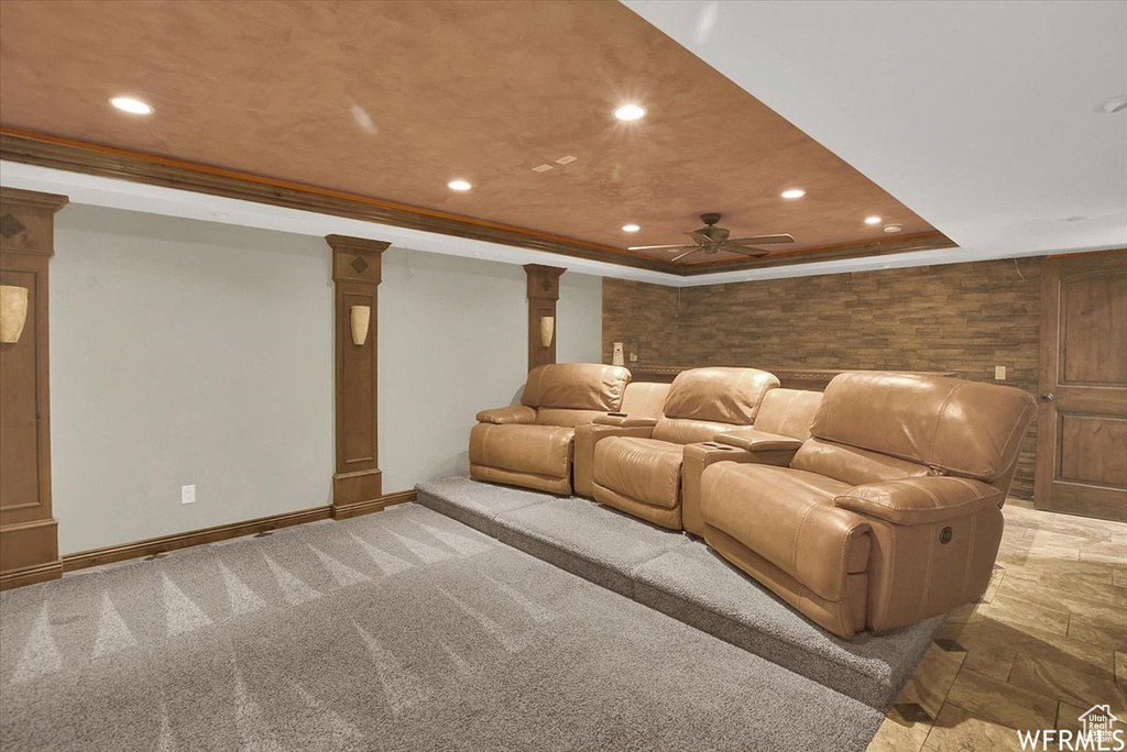 Cinema room featuring decorative columns, ceiling fan, and a tray ceiling