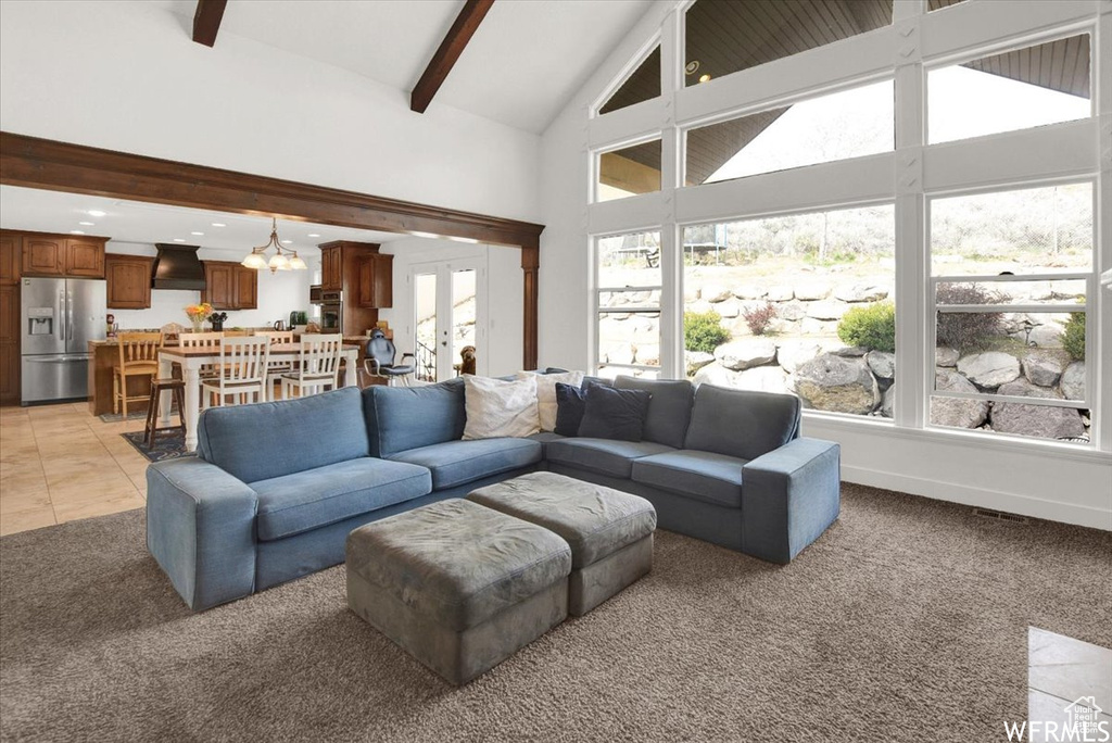 Living room featuring french doors, beam ceiling, light tile patterned floors, and high vaulted ceiling