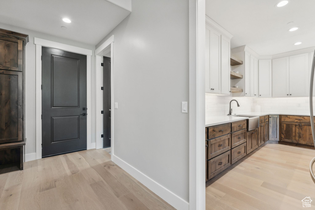 Hallway with light hardwood / wood-style flooring and sink