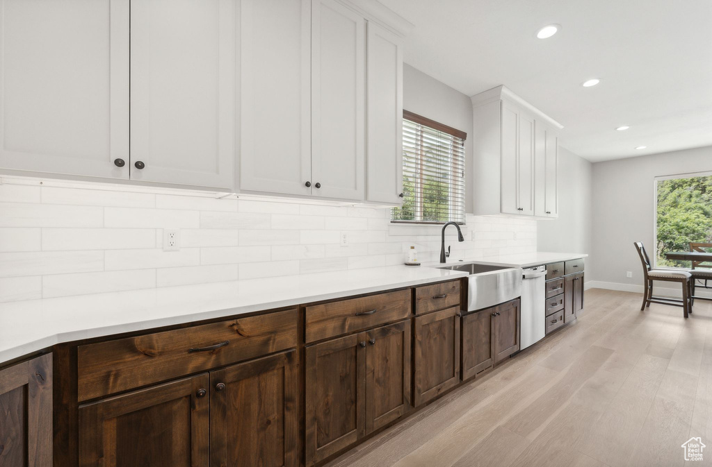 Kitchen featuring plenty of natural light, sink, light hardwood / wood-style flooring, and tasteful backsplash