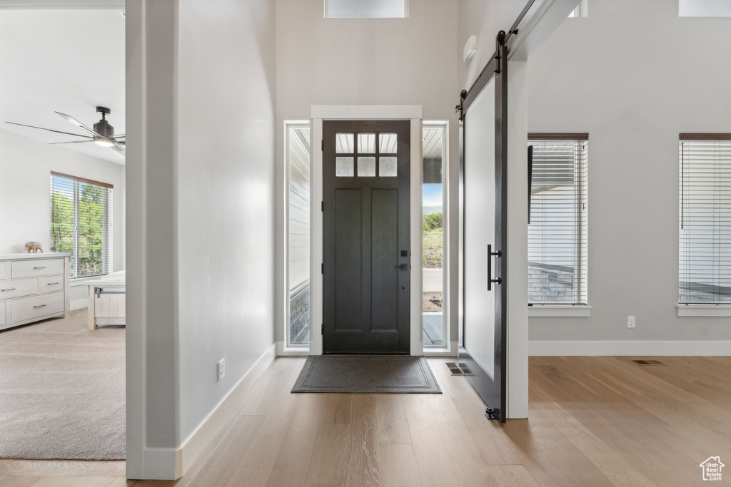 Carpeted entrance foyer with a barn door, ceiling fan, and a high ceiling