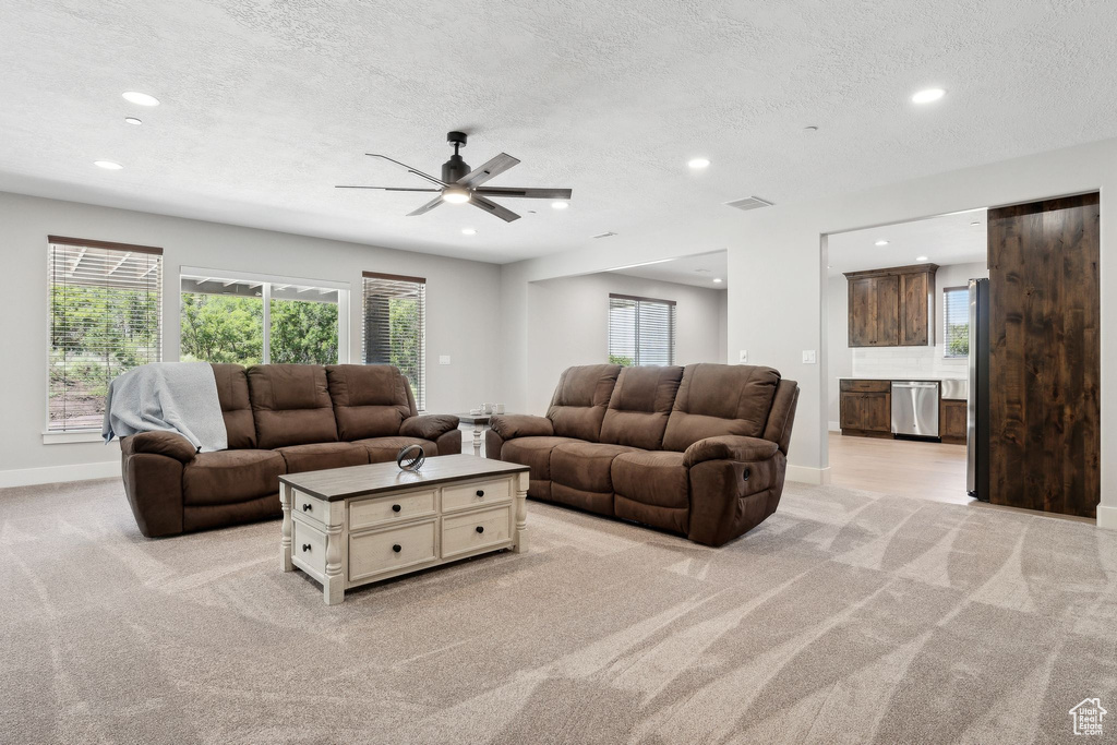 Carpeted living room featuring a textured ceiling and ceiling fan