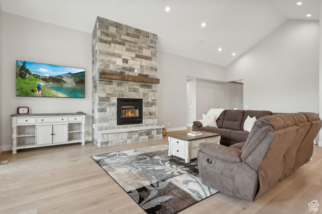 Living room featuring a fireplace, light hardwood / wood-style floors, and high vaulted ceiling