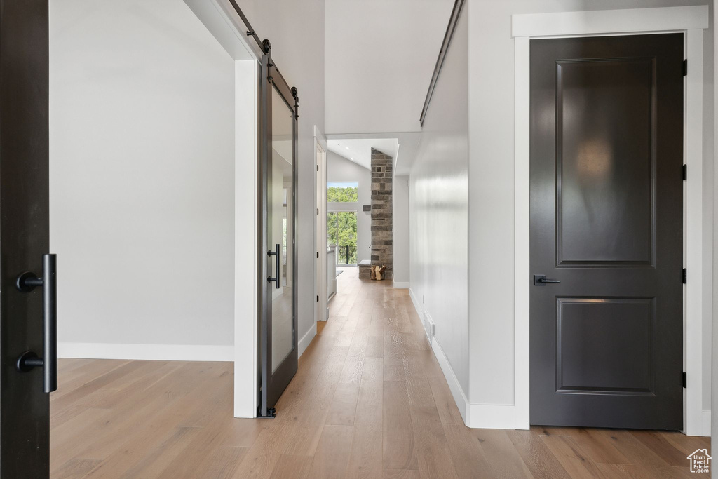 Hall with light wood-type flooring and a barn door