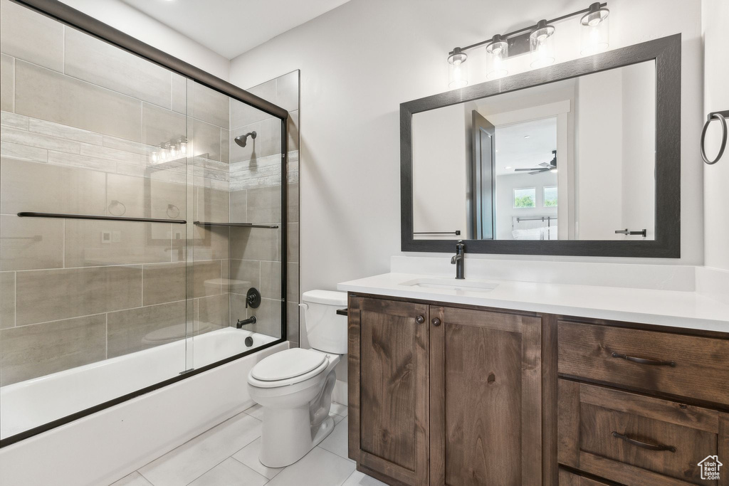 Full bathroom featuring tile patterned flooring, enclosed tub / shower combo, toilet, vanity, and ceiling fan