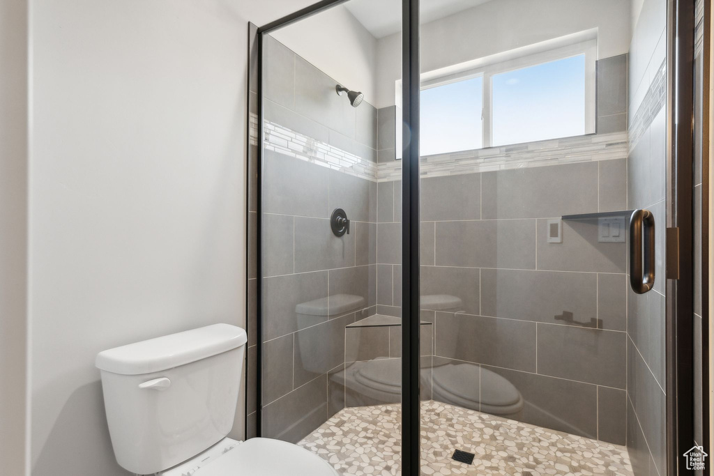 Bathroom featuring a shower with shower door and toilet