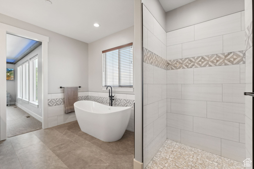 Bathroom featuring tile walls, tile patterned floors, and plus walk in shower