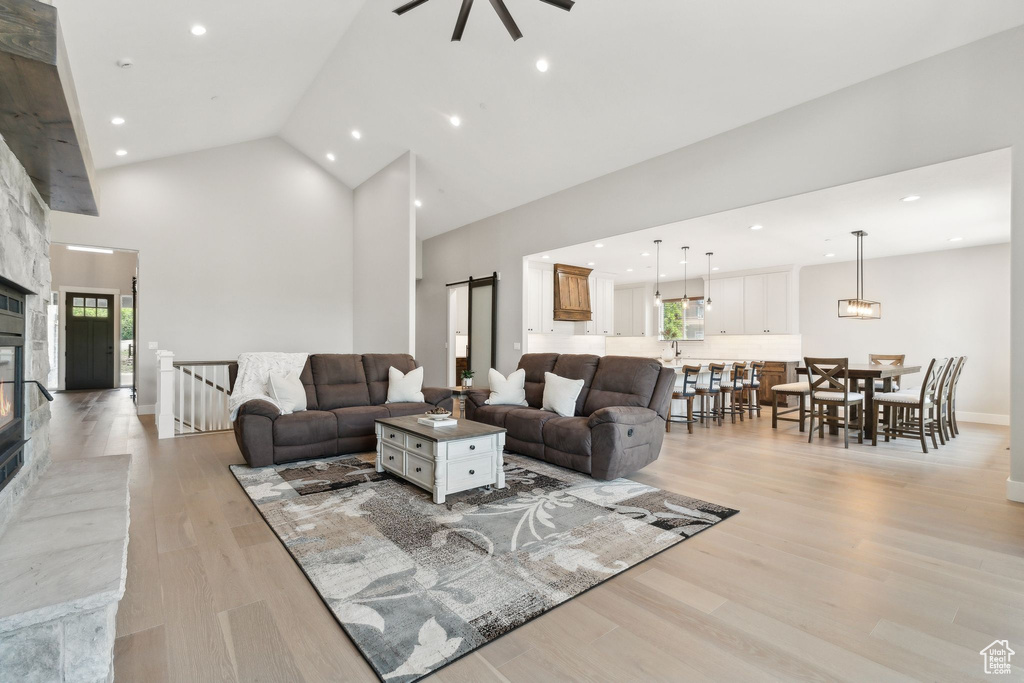 Living room with high vaulted ceiling, light hardwood / wood-style flooring, and a healthy amount of sunlight