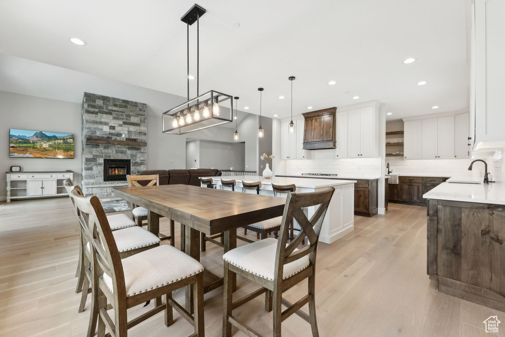 Dining space featuring a stone fireplace, sink, and light wood-type flooring