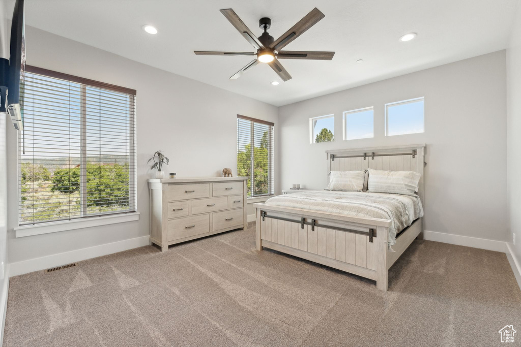 Bedroom featuring multiple windows, ceiling fan, and light colored carpet