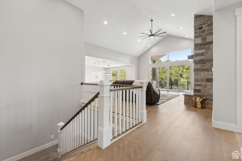 Hall with high vaulted ceiling and light hardwood / wood-style floors