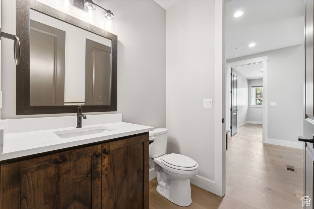 Bathroom featuring hardwood / wood-style flooring, toilet, and vanity