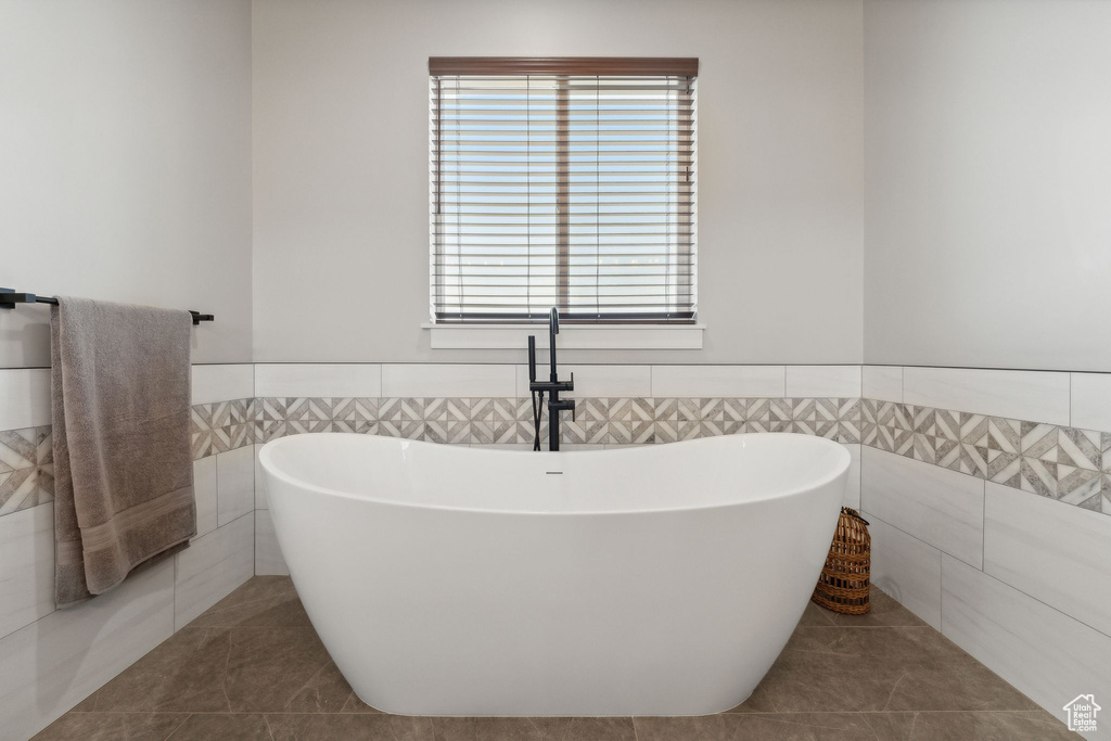 Bathroom featuring tile walls, a bathtub, and tile patterned floors