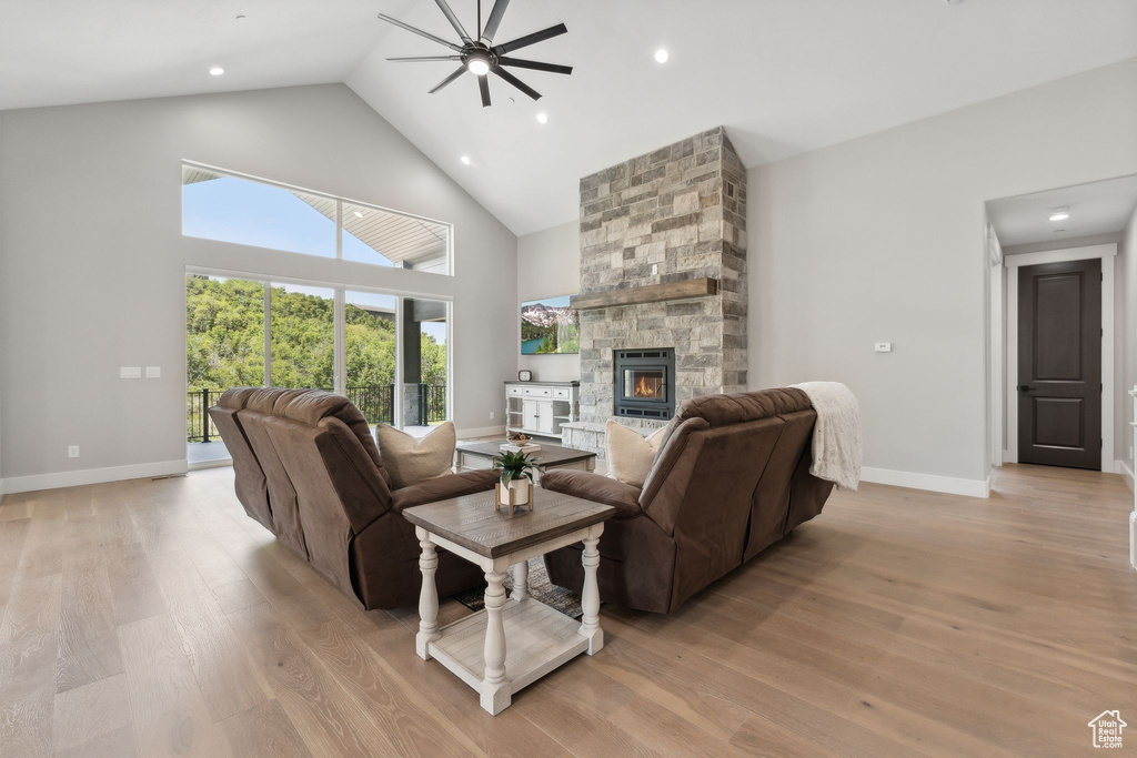 Living room with high vaulted ceiling, a fireplace, ceiling fan, and light hardwood / wood-style flooring