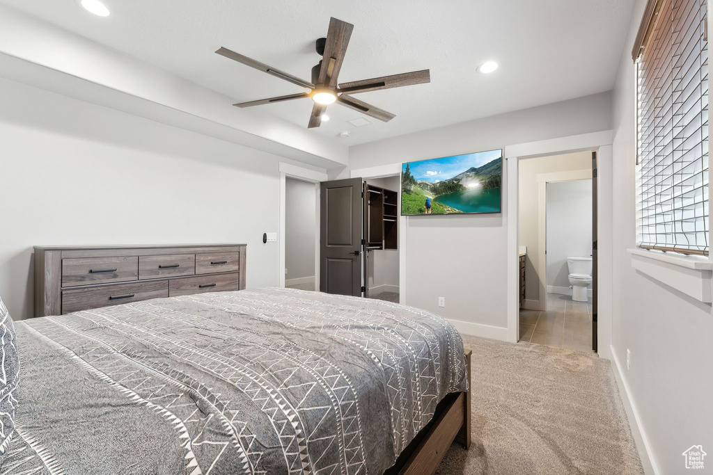 Bedroom with light carpet, ensuite bath, and ceiling fan