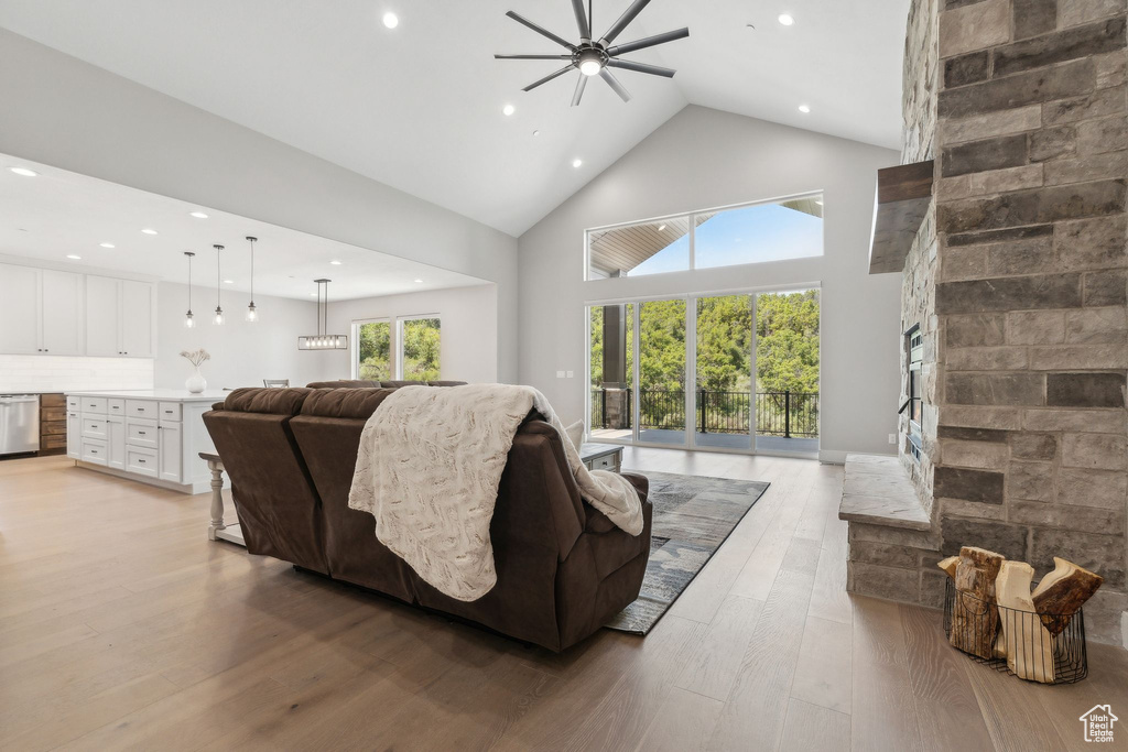 Living room featuring ceiling fan, a fireplace, light hardwood / wood-style floors, and high vaulted ceiling