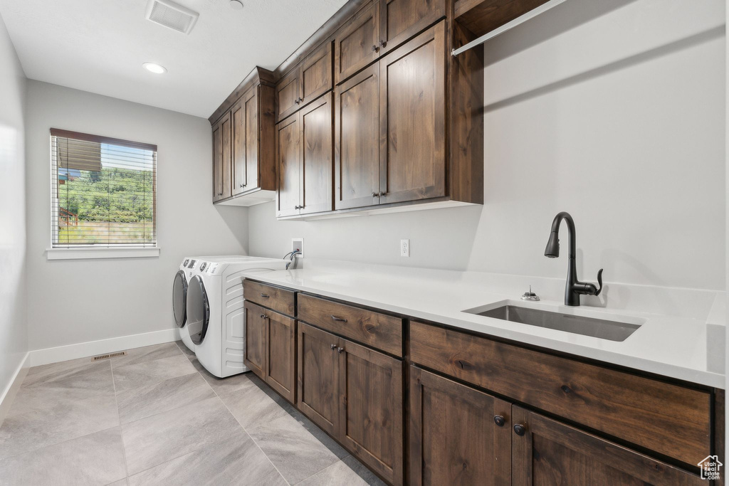 Clothes washing area featuring cabinets, sink, light tile patterned flooring, and washer and clothes dryer