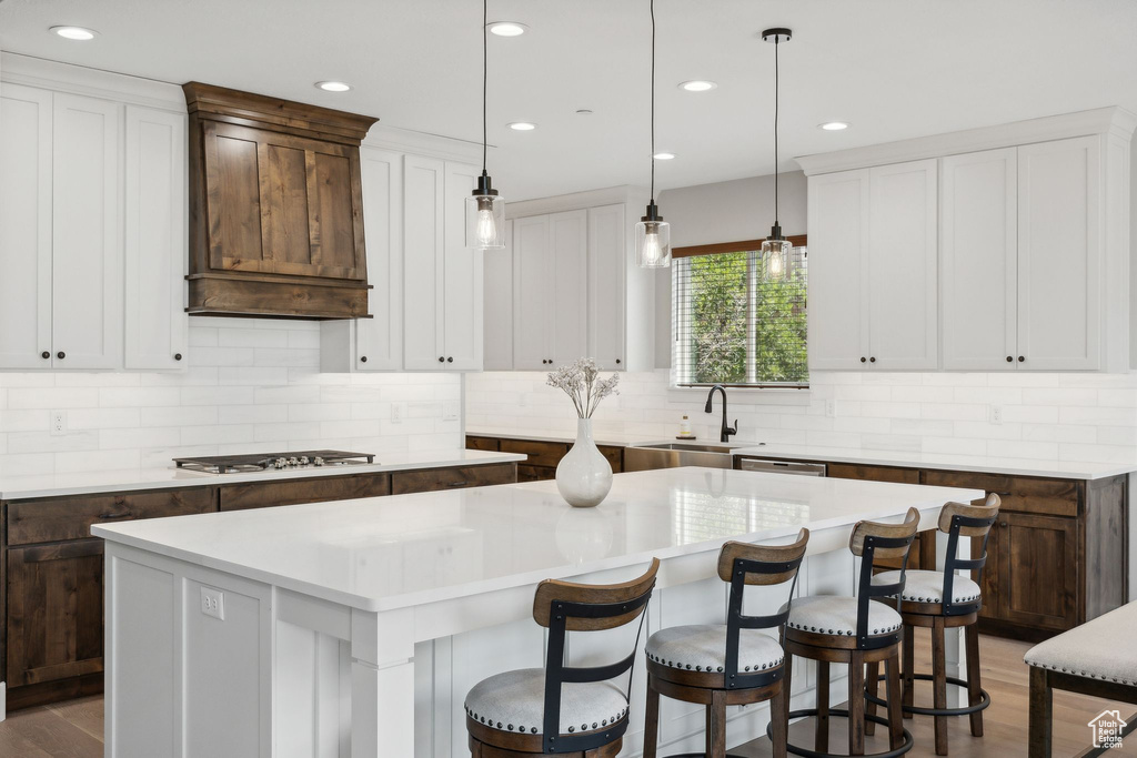 Kitchen featuring backsplash, decorative light fixtures, sink, and a kitchen island