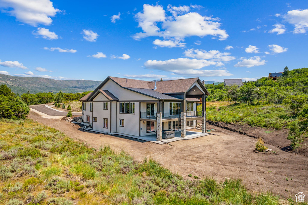 Back of house with a mountain view and a balcony