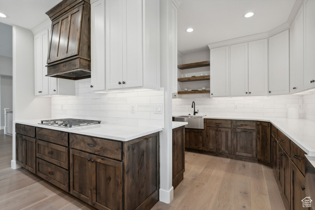 Kitchen featuring backsplash, sink, light hardwood / wood-style floors, and custom range hood