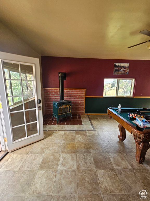 Playroom with a wood stove, a wealth of natural light, tile patterned flooring, and ceiling fan