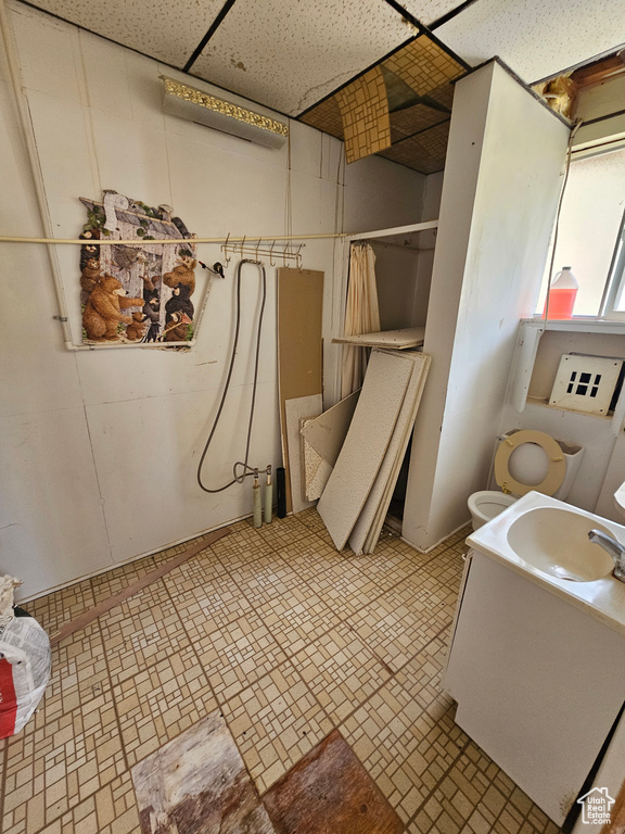 Bathroom with sink, toilet, tile patterned flooring, and a paneled ceiling