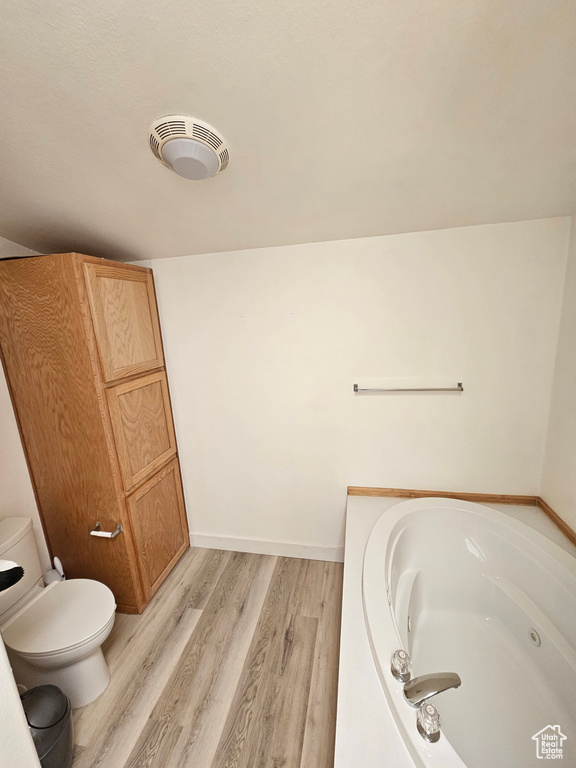 Bathroom featuring wood-type flooring, toilet, and a tub