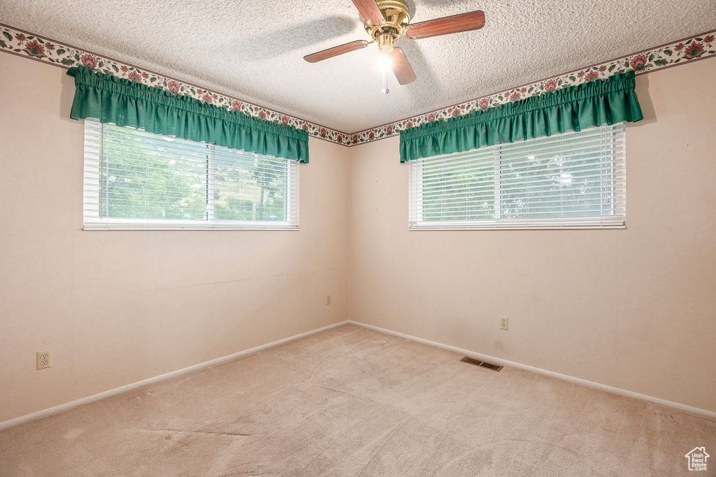 Carpeted empty room featuring a textured ceiling and ceiling fan