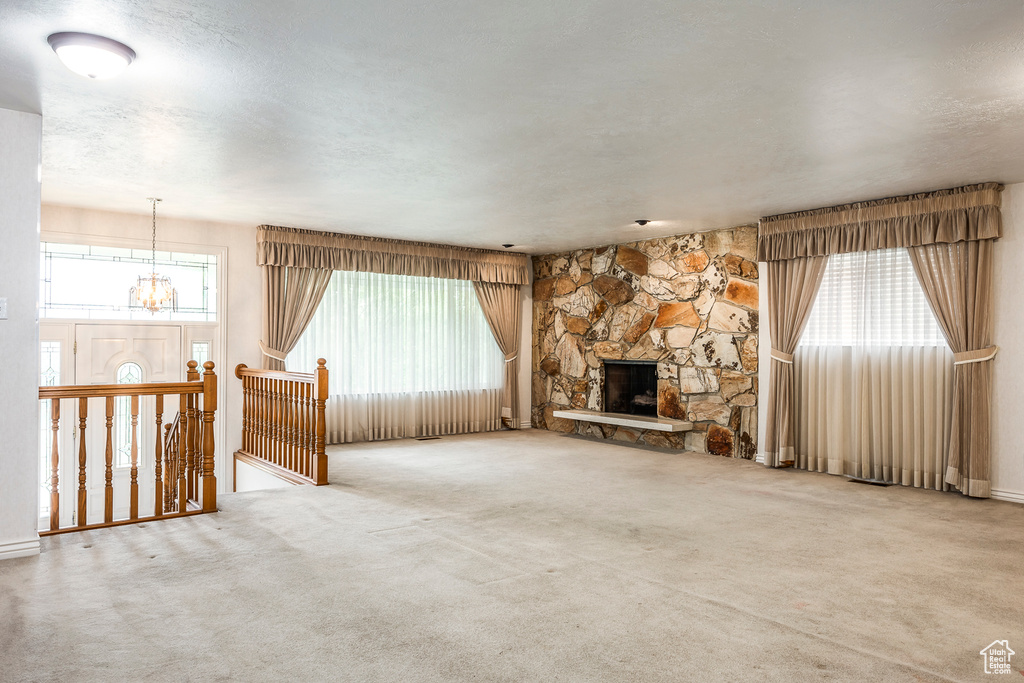 Unfurnished living room with a notable chandelier, carpet, and a fireplace