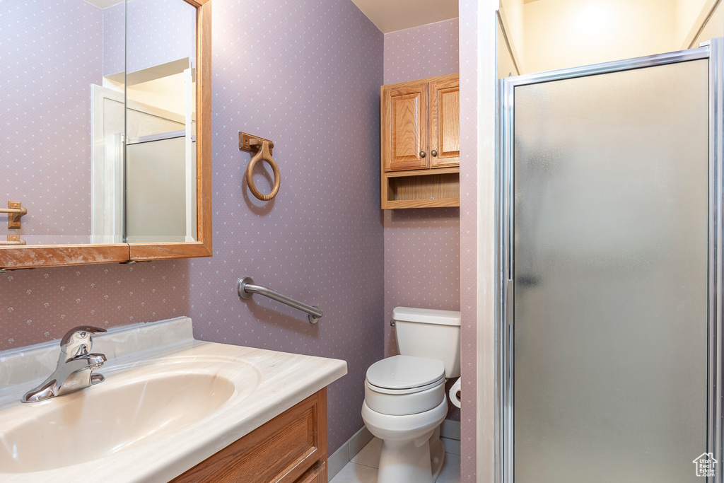 Bathroom featuring a shower with door, vanity, tile patterned flooring, and toilet