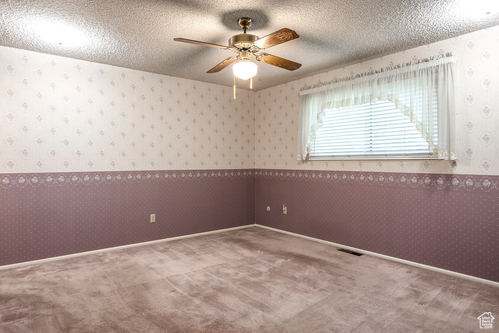 Carpeted empty room with ceiling fan and a textured ceiling