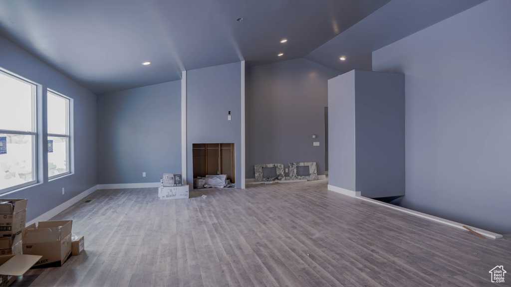 Unfurnished living room featuring vaulted ceiling and hardwood / wood-style floors