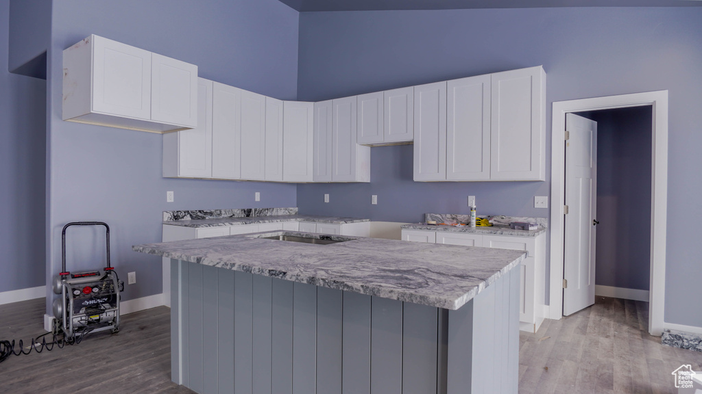 Kitchen with white cabinets, light hardwood / wood-style flooring, and a kitchen island