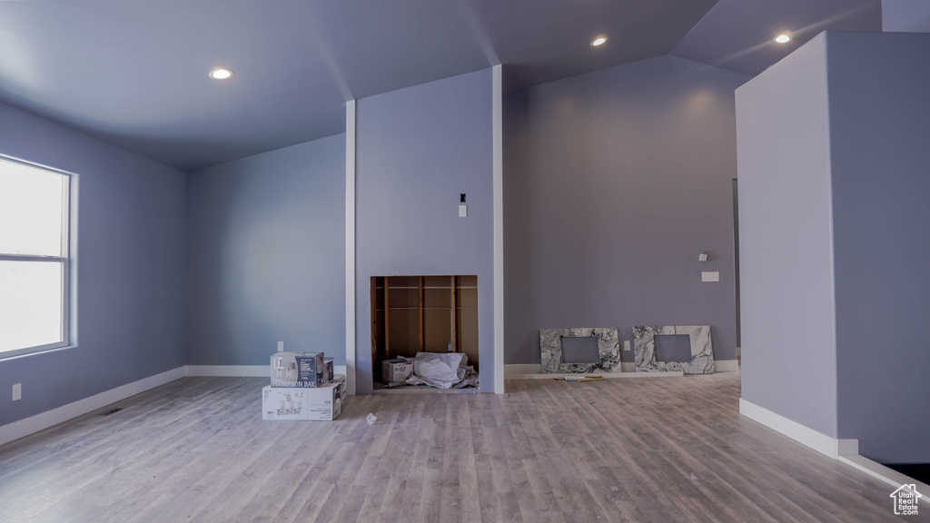 Unfurnished living room featuring hardwood / wood-style flooring and lofted ceiling