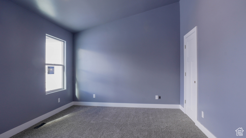 Carpeted spare room with vaulted ceiling